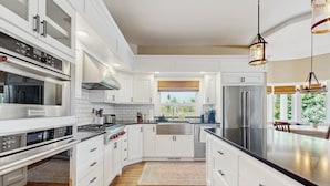 A modern kitchen with white cabinetry, stainless steel appliances, and a large island. - Plummer Lakefront Home: Fish & Kayak (Centralia)