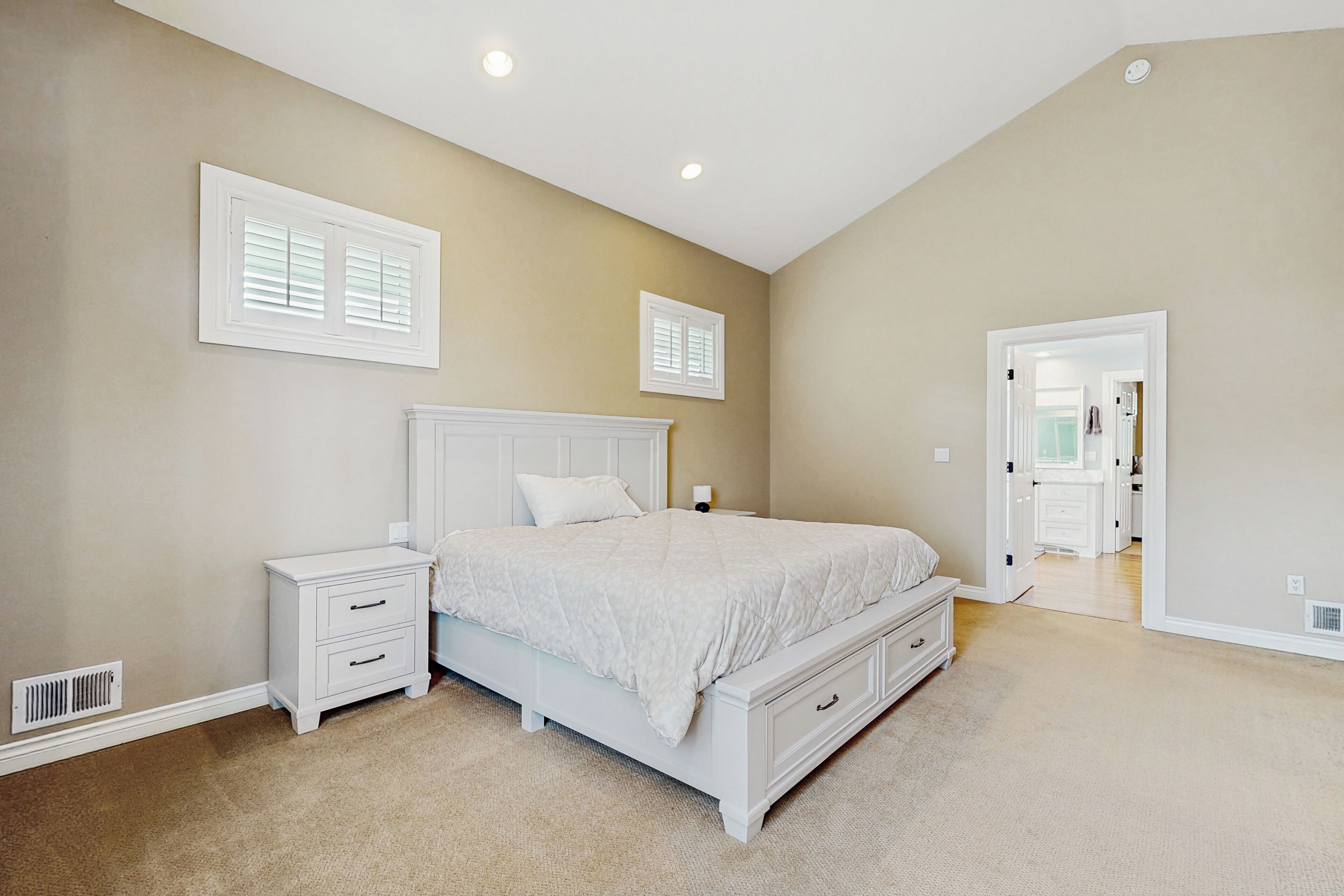 A bedroom with a white bed, nightstands, and a walk-in closet.