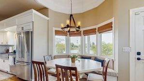 A modern kitchen with a built-in refrigerator, a dining table surrounded by chairs, and large windows with a view of greenery. - Plummer Lakefront Home: Fish & Kayak (Centralia)