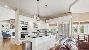 A spacious kitchen with white cabinetry, a central island, stainless steel appliances, and pendant lighting. - Plummer Lakefront Home: Fish & Kayak (Centralia)