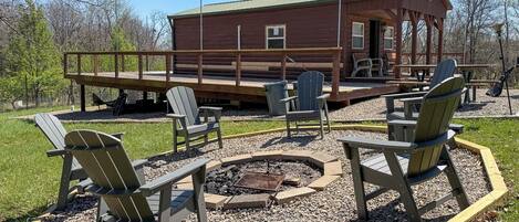 Eine Holzhütte mit einer Terrasse, Sitzgelegenheiten im Freien und einer Feuerstelle.