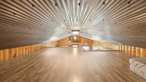 A spacious attic room with wooden walls and a sloped ceiling. - Fishing Pond & Treehouse: Tranquil Maysville Cabin (Maysville)