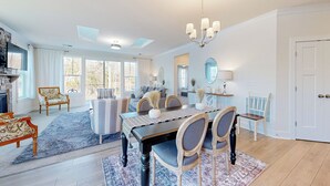 A spacious living room with a fireplace, a dining area with a long table and chairs, and a cozy seating area with a sofa and armchairs. - 3BR Riverfront Home w/ Kayaks & Game Room (Seaford)