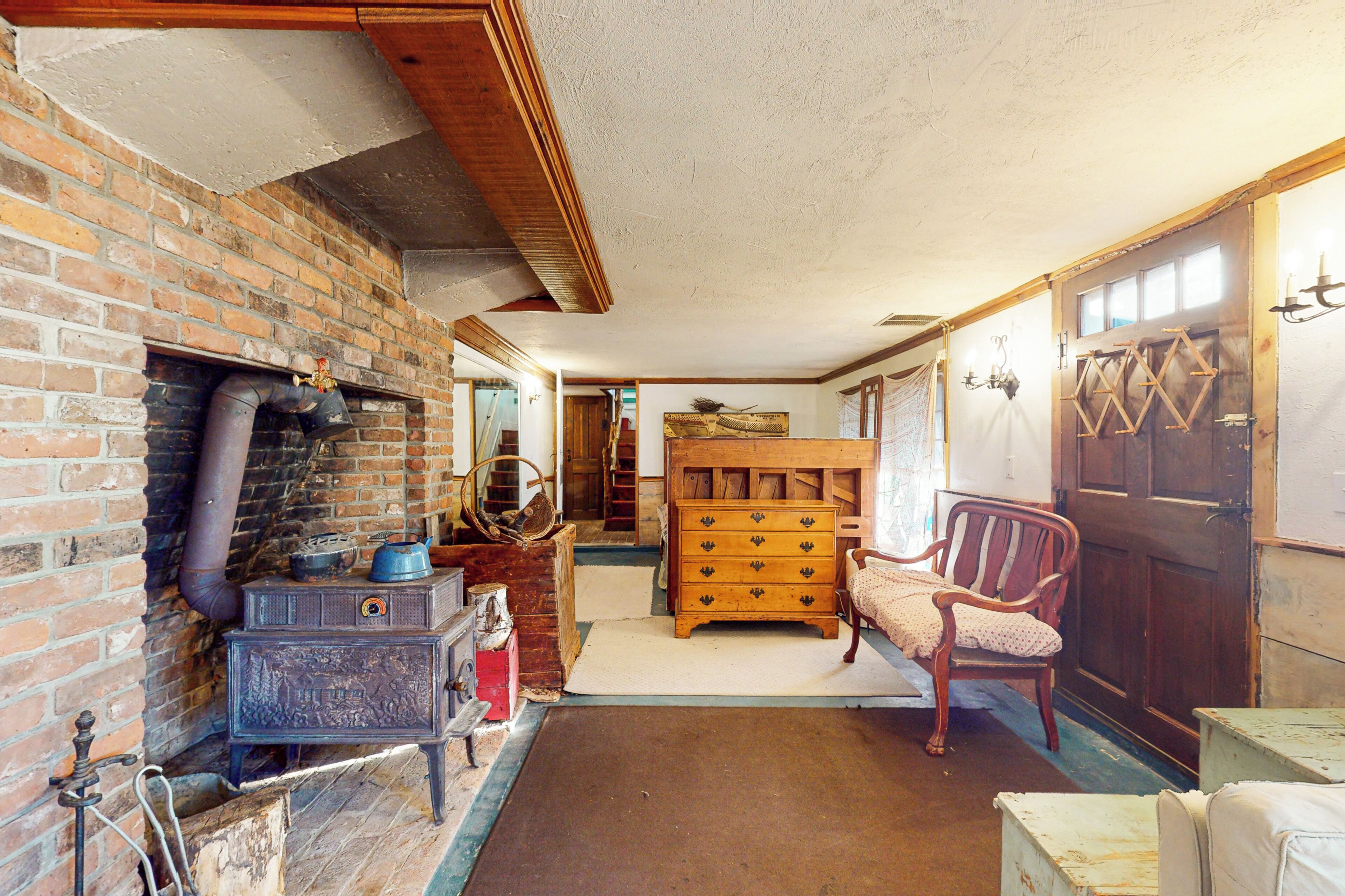 A rustic room with a brick fireplace, wooden dresser, and a wooden chair.