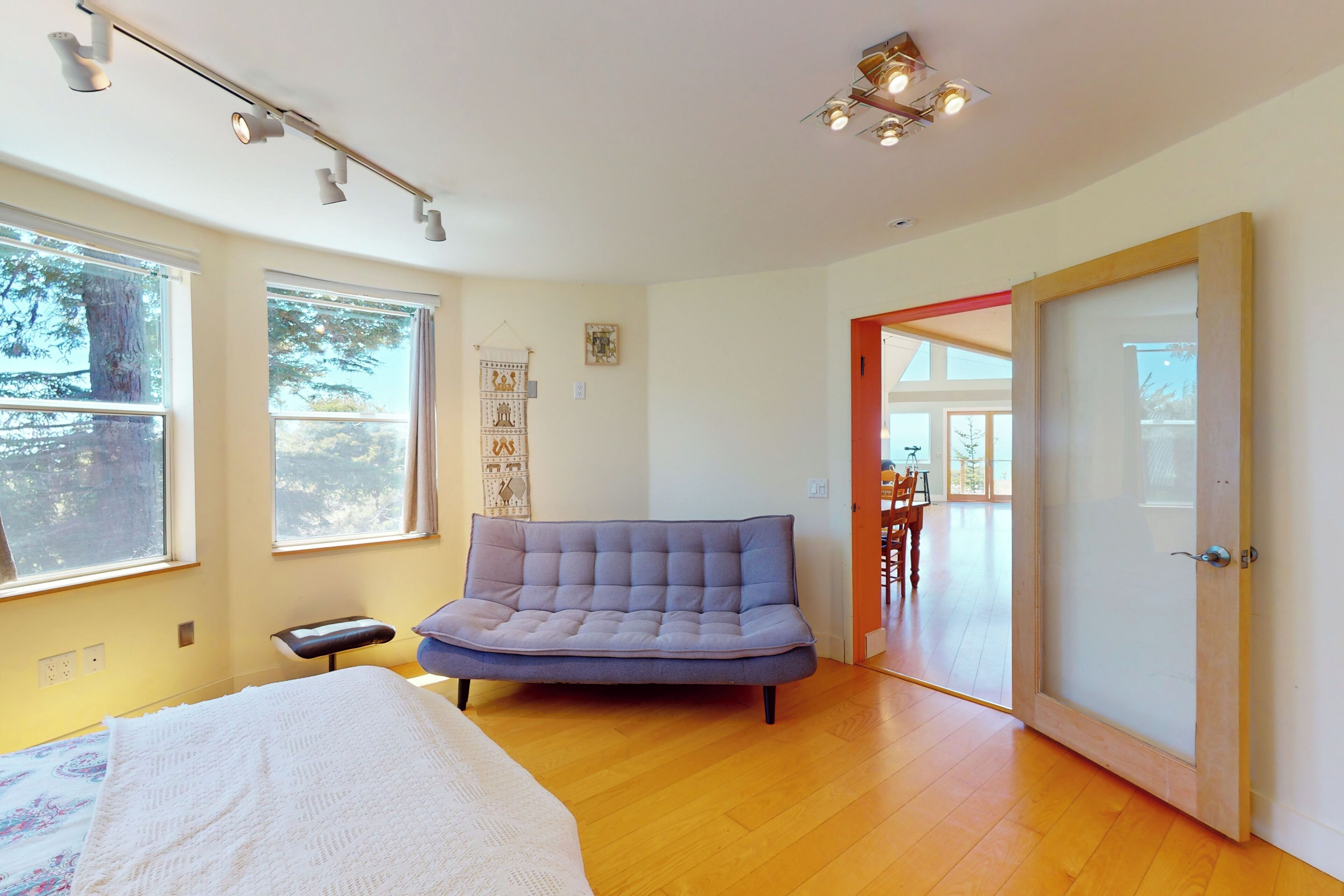 Ein Schlafzimmer mit einem Bett, einem Schlafsofa, einem Fenster und einer Tür zu einem Essbereich.