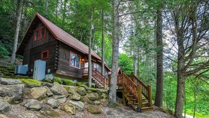 A rustic cabin with a wooden staircase leading to a deck, surrounded by trees. - Beautiful Wood Cabin in Red River Gorge (Rogers)