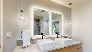 A bathroom with two white sinks, a large mirror, and a towel hanging on the left. - Home w/ Stunning River Views & Nearby Attractions (Myrtle Creek)