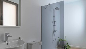 Et moderne badeværelse med vask, toilet og bruser.