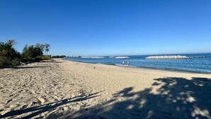 Ein sandiger Strand mit Felsen und klarem, blauem Wasser.