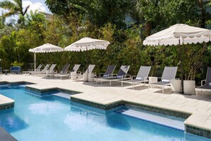 A pool area with lounge chairs and umbrellas. - Waterfront Elegance Near Cruiseport | Pool & Gym (Fort Lauderdale)