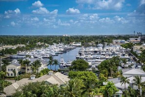 Un port de plaisance où sont amarrés de nombreux bateaux, entouré de bâtiments résidentiels et d’une végétation luxuriante.