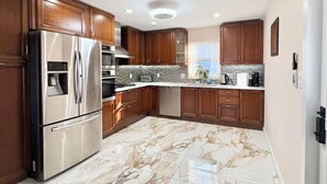 A modern kitchen with wooden cabinets, stainless steel appliances, and a marble floor. - Home in Mount Pocono, Hot tub, Sauna, Lakefront, Kayaks+ (Pocono Summit)