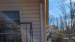 A wooden deck with a metal railing, a covered porch area, and a kayak resting against the house. - Home in Mount Pocono, Hot tub, Sauna, Lakefront, Kayaks+ (Pocono Summit)