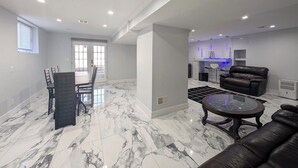 A spacious living area with a dining table and chairs, a leather sofa, and a kitchen area with a blue-lit bar. - Home in Mount Pocono, Hot tub, Sauna, Lakefront, Kayaks+ (Pocono Summit)