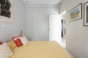 Ein Schlafzimmer mit einem Bett, Kissen, einem Kleiderschrank und einer Tür zu einem anderen Raum.