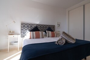 Ein Schlafzimmer mit Bett, Kissen, Nachttisch, Lampe und Kleiderschrank.
