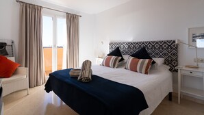 A hotel room with a bed, a desk, a chair, and a window with curtains. - Sea Views Lagos de Santa Maria - By Time and Home (Marbella)