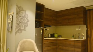 A modern kitchen with wooden cabinets, a built-in oven, and a countertop with a sink. - Luxury Skyline Studio • Near Cyberhub & Metro • NirviiHomes (Gurugram)