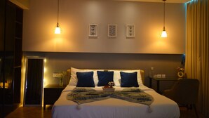 A modern hotel room with a neatly made bed, a bedside table with a vase of flowers, and a wall-mounted artwork. - Luxury Skyline Studio • Near Cyberhub & Metro • NirviiHomes (Gurugram)