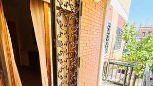A balcony with a tiled floor, a metal gate, and a brick wall.