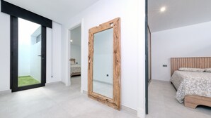 Un dormitorio moderno con un espejo grande, una cama con cabecera de madera y una puerta corredera que da a un balcón.