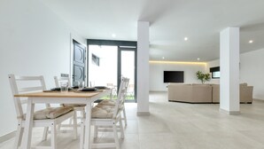 Una sala de estar moderna con comedor, que incluye un sofá, un televisor y una planta.
