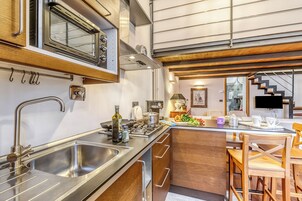 A modern kitchen with stainless steel appliances, wooden cabinets, and a dining area with wooden chairs.