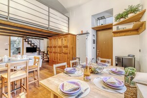 A dining area with wooden furniture, a table set for four, and a staircase leading to an upper level.