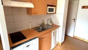 Une cuisine compacte avec des meubles en bois, un four à micro-ondes, un évier et un lave-vaisselle.