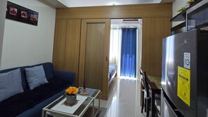 A modern living room with a sofa, coffee table, and a refrigerator. - WELCOME TO YOUR HOME AWAY FROM HOME. OUR UNIT HAS COMPLIMENTARY SECURE PARKING (Pasay City)