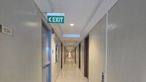 A long, well-lit hallway with a clear exit sign, a fire extinguisher, and a door marked with the number 926. - WELCOME TO YOUR HOME AWAY FROM HOME. OUR UNIT HAS COMPLIMENTARY SECURE PARKING (Pasay City)