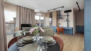 Een moderne woonkamer met een eethoek, een bank, een televisie en uitzicht op de stad.