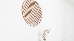 Une chambre à coucher avec une tête de lit rembourrée de couleur grise, une table de chevet en bois, une lampe de chevet et une couvre-lit bleue à motifs.