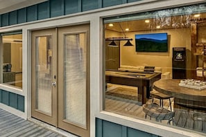 A modern interior with a dining area, a sofa, and a television. - Susie's Cottage: pool • hot tub • fire pit • bunks (Gatlinburg)