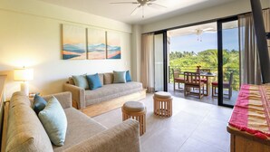 Een ruime woonkamer met een bank, poefs, een tafel en een balkon met uitzicht.