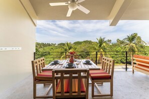 A dining area with a table set for four, a ceiling fan, and a view of lush greenery. - Short Walk to Beach & Town · Top Floor · Solana (Huatulco)