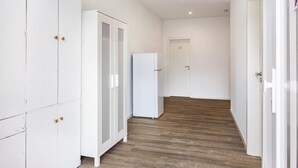 A hallway with white cabinets, a white refrigerator, and a wooden floor.