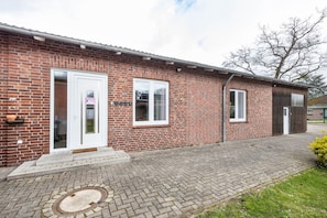A brick building with a white door, a window, and a small porch area.