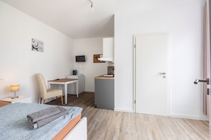 A hotel room with a bed, a desk, a chair, a television, and a door.