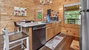 Ein Holzblockhaus mit Küche, Essbereich und großem Fenster.