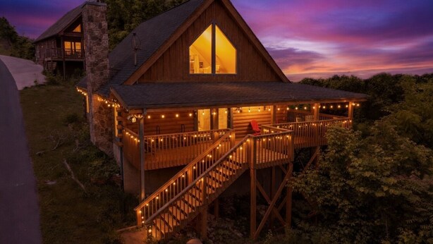 Eine Holzhütte mit Balkon, Treppe und Lichterkette.