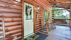 Eine Holzhütte mit Veranda, Schaukelstuhl, einer Willkommensschild und einer Tür mit einem Kranz.