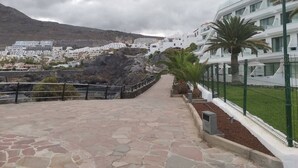 Un sendero de piedra que conduce a la costa, con edificios blancos y una montaña al fondo.