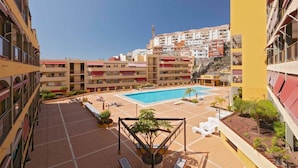 Un patio de hotel con piscina, varios balcones y vistas de edificios circundantes.