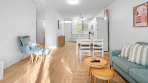 Ein modernes Wohnzimmer mit einem blauen Sofa, einem kleinen runden Tisch und einem Essbereich mit weißen Stühlen.