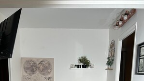 Ein Essbereich mit einem runden Tisch und zwei Stühlen, einer Weltkarte an der Wand und einer kleinen Pflanze auf einem Regal.