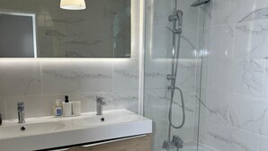 Ein modernes Badezimmer mit einem Doppelwaschtisch, einer Duschkabine und Marmorfliesen.