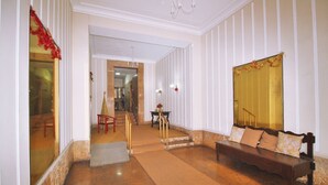 Un hall d’entrée avec un banc en bois, un escalier et un miroir au mur.