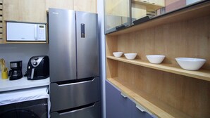 Une cuisine moderne équipée d’un four à micro-ondes encastré, d’une machine à café et d’un réfrigérateur en acier inoxydable.