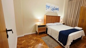 Une chambre d’hôtel avec un lit, des tables de chevet, une armoire en bois et des œuvres d’art accrochées au mur.